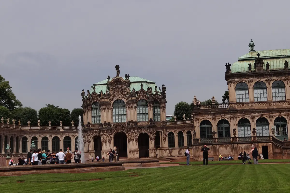 Zwinger-gårdspladsen med en græsplæne foran, Wallpavillon i midten og den næste pavillon til højre under et grønt tag.