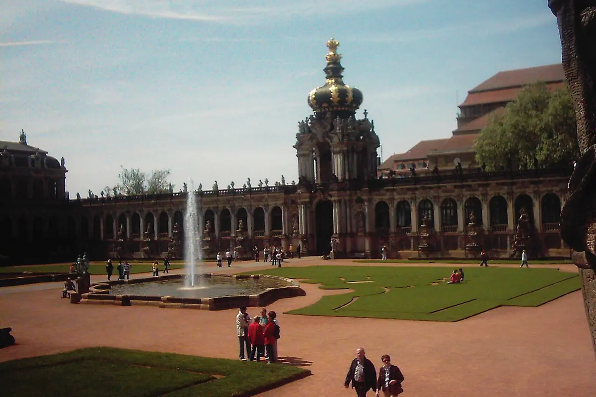 Krongeporten over Zwinger-gårdspladsen, med en fontæne og en græsplæne foran og det lange galleri ved siden af.