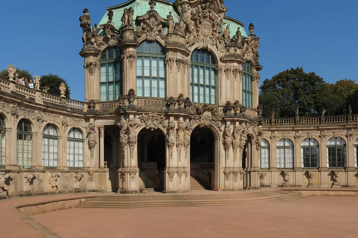 Wallpavillon set fra gårdspladsen mod en blå himmel med et par buede indgange i stueetagen og et buet galleri ved siden af.
